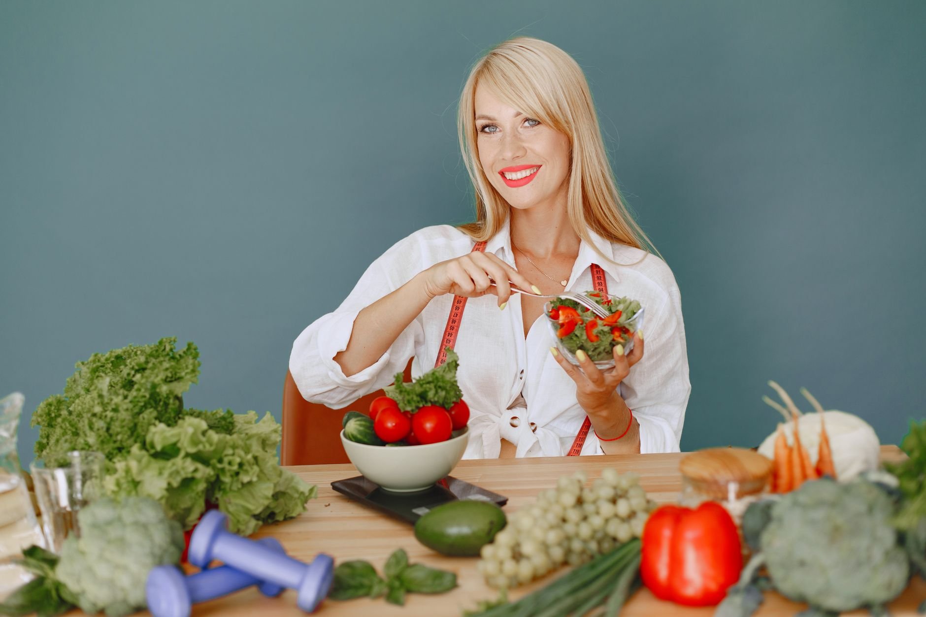 Person enjoying a fresh salad surrounded by vegetables, promoting healthy eating.